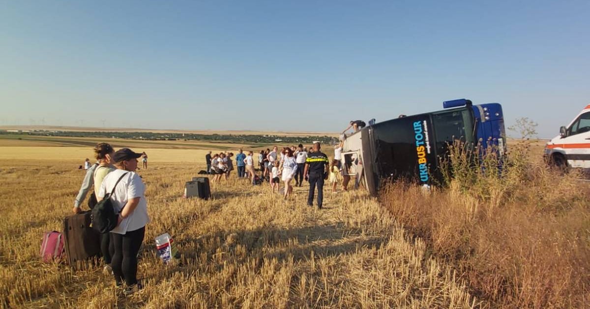 Autocarul cu ucraineni s-a răsturnat în câmp, iar mai multe persoane se văd în lanul de grâu stând în picioare cu valizele lângă ele