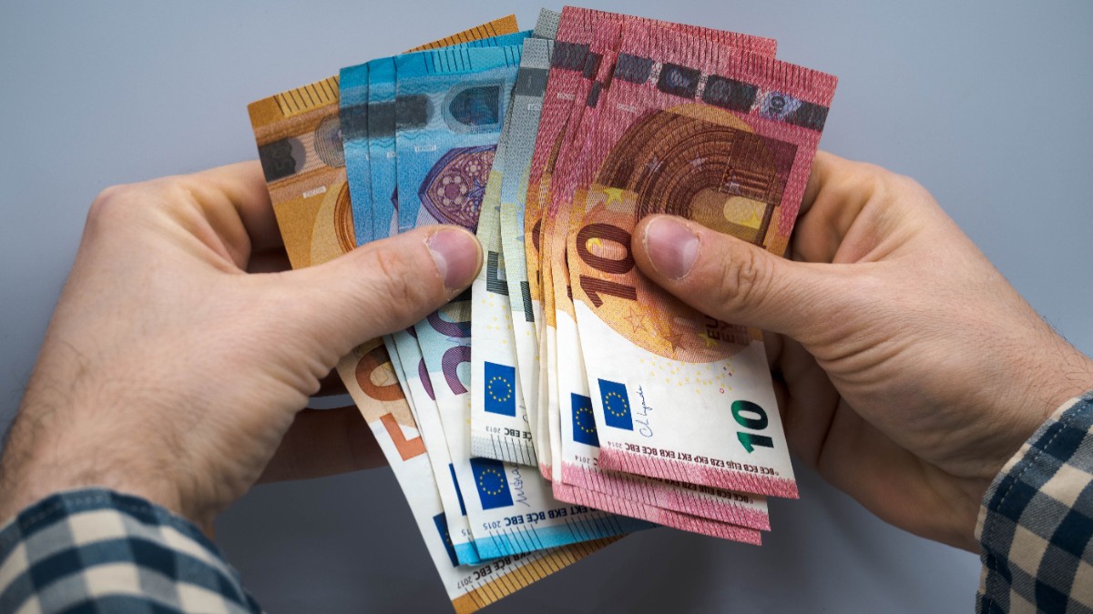 Un bărbat care ține mai multe bancnote de euro în mâini