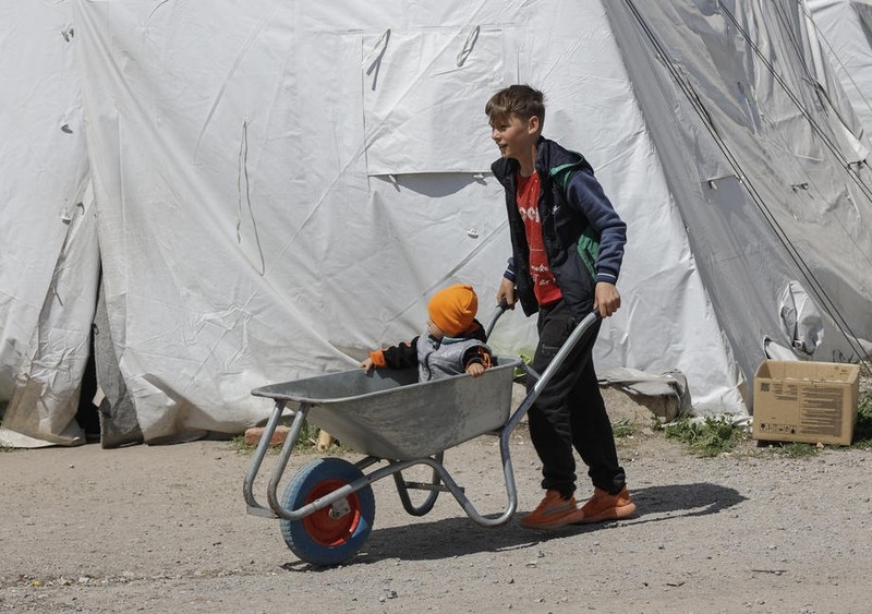 Un copil mai mare, evacuat de la Azovstal, își plimbă frățiorul mai mic cu o roabă. Imagine din 7 mai, de la centrul de triere de la Bezimene