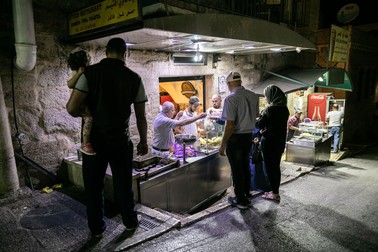 Pe seară, localnici din Betleem cumpără falafel de la un comerciant care gătește direct în stradă