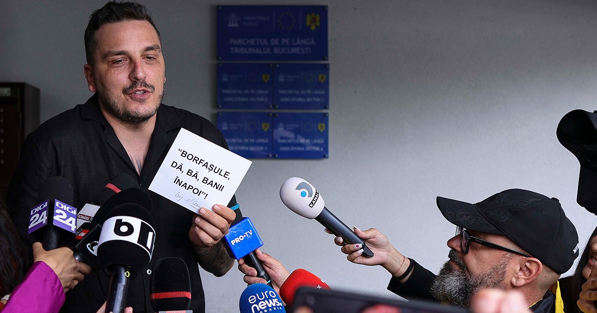 Makaveli înconjurat de jurnaliști ține o foaie în mână pe care scrie: ”Borfașule, dă, bă, banii înapoi!”
