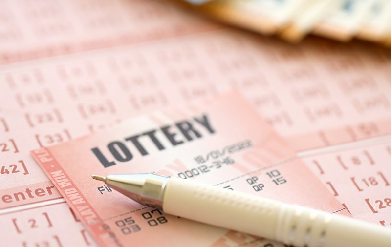 Un pix pe un bilet la loto. În fundal se văd mai multe bancnote 