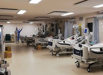 Fotografie făcută luni, 18 octombrie, la spitalul modular de la Piatra Neamț. Pe fundal, doi dintre angajații spitalului care au în grijă pacienții internați aici cu COVID