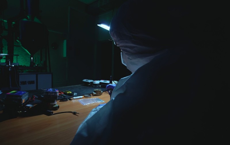 Un cercetător în combinezon, într-un laborator improvizat