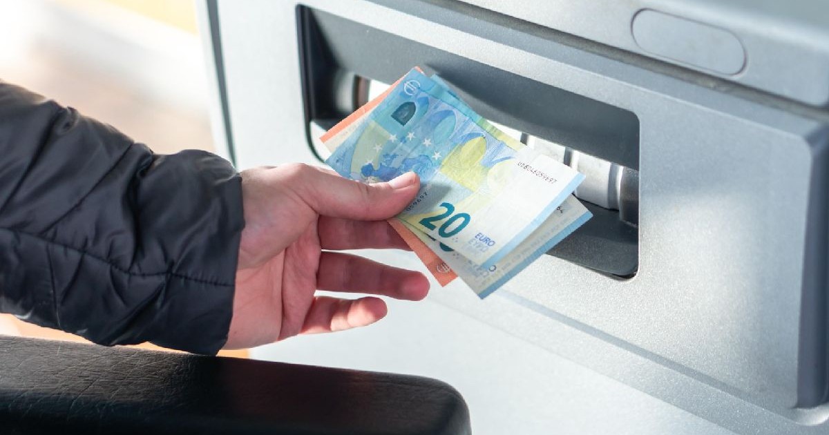 Imaginea arată o persoană care retrage bancnote euro dintr-un bancomat