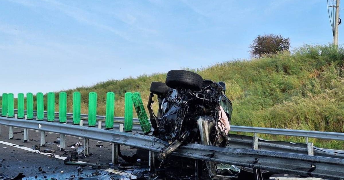 O mașină distrusă complet e lipită peste balustrada drumului expres ca o cutie de tinichea turtită
