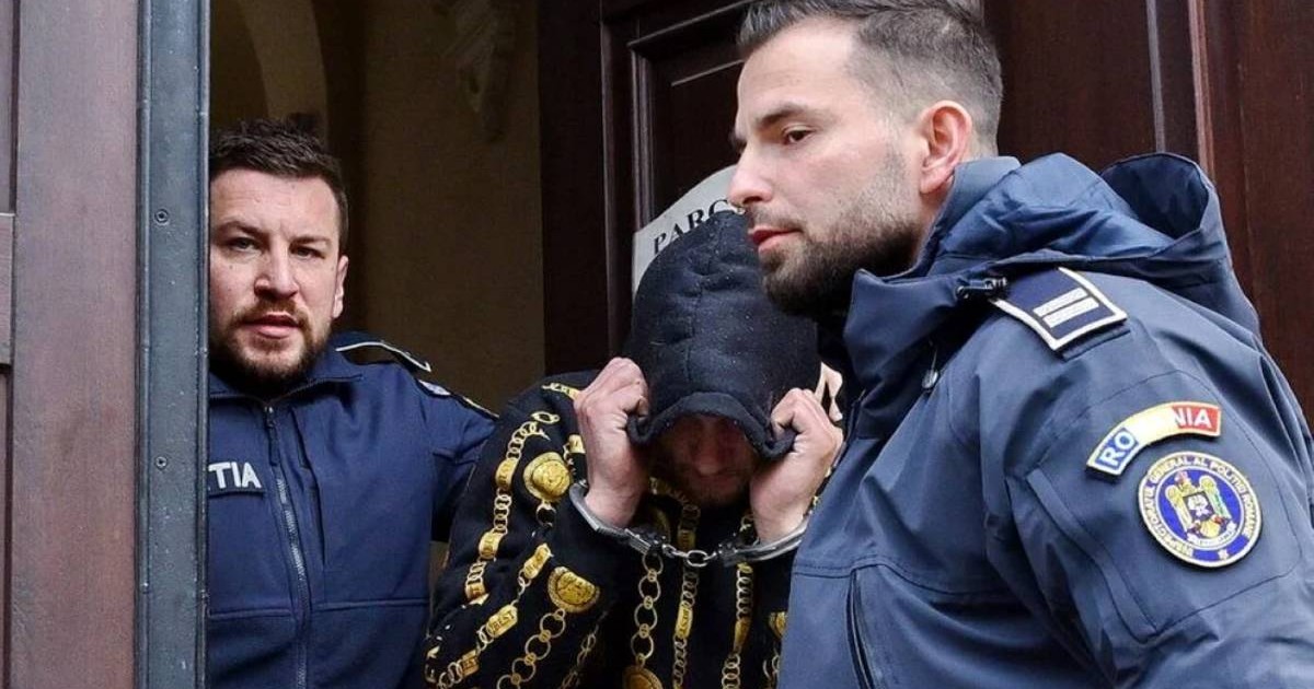 Un barbat încătusat, cu mainile legate ridicate la cap, langa el doi politisti