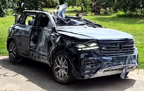 masina suv parcata in fata unui gazon. masina neagra este aproape distrusa