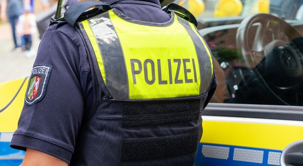 Un polițist văzut de la spate lângă o mașină de poliție