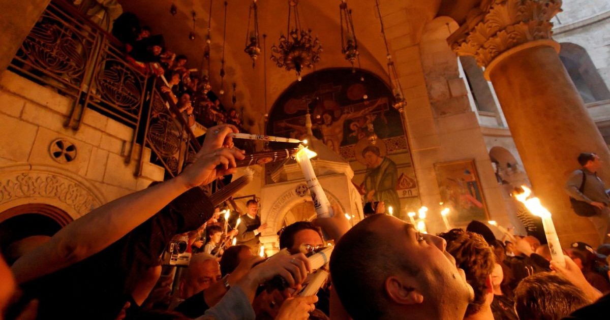 Credinciosi in biserica cu lumânări aprinse iau lumina Sfantă de PAște