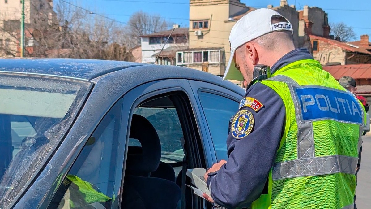 Un polițist verifică actele unui șofer dintr-o mașină neagră