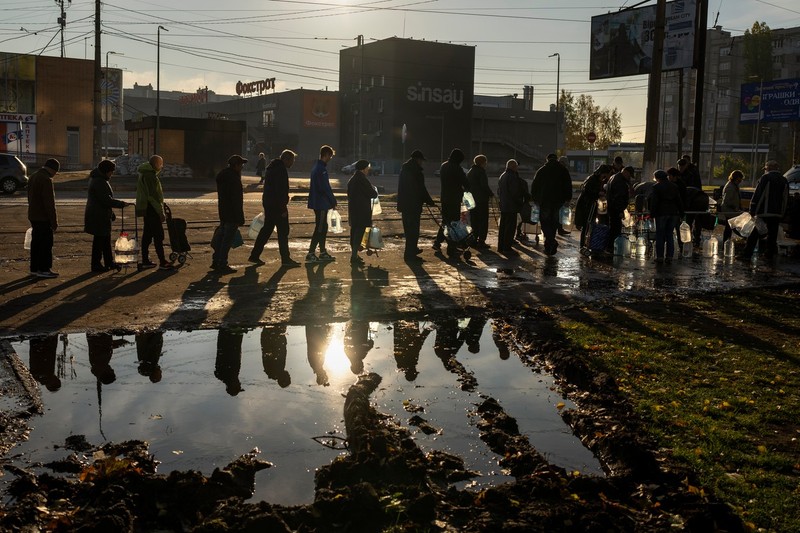 Oameni care stau la coadă cu sticle de plastic pentru a-și face provizii de apă potabilă dintr-un rezervor din centrul orașului Mikolaiv, luni, 24 octombrie 2022 | Foto: Profimedia