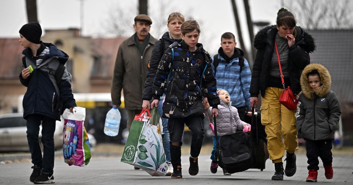 Refugiați din Ucraina se adună în fața unui adăpost temporar pentru refugiați, fost supermarket TESCO abandonat, după ce au fost transportate de la granița polono-ucraineană, pe 29 martie 2022, în Przemysl, Polonia