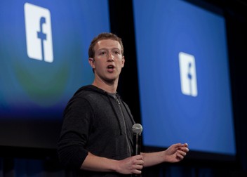 Facebook face concedieri pentru prima dată în istoria sa. Zuckerberg cu logo-uri Facebook ]n spate