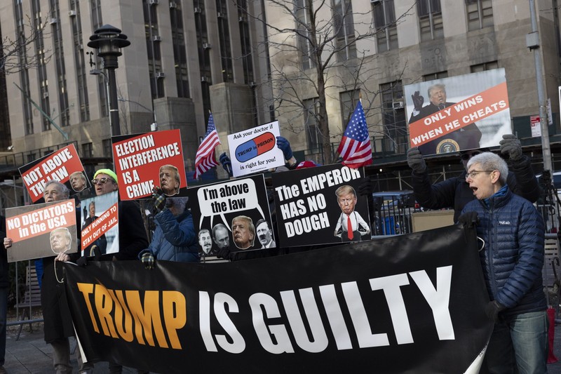 Protesters with the activist group Rise &amp; Resist hold signs and banners outside the Manhattan Criminal Courthouse waiting for Former President Donald Trump's arrival at a hearing in the hush money Stormy Daniels case. A banner reads ''Trump is guilty.'' Protesters hold signs with images of Joseph Stalin, Vladimir Putin, Adolf Hitler and Donald Trump with a quote bubble that reads “I’m above the law” and signs that read ''Only wins when he cheats'' ''Ask your doctor if Trump in prison is right for you'' ''The emperor has no dough'' ''Election interference is a crime'' ''Only running to stay out of jail'' ''No dictators in the USA'' ''Not above the law.”