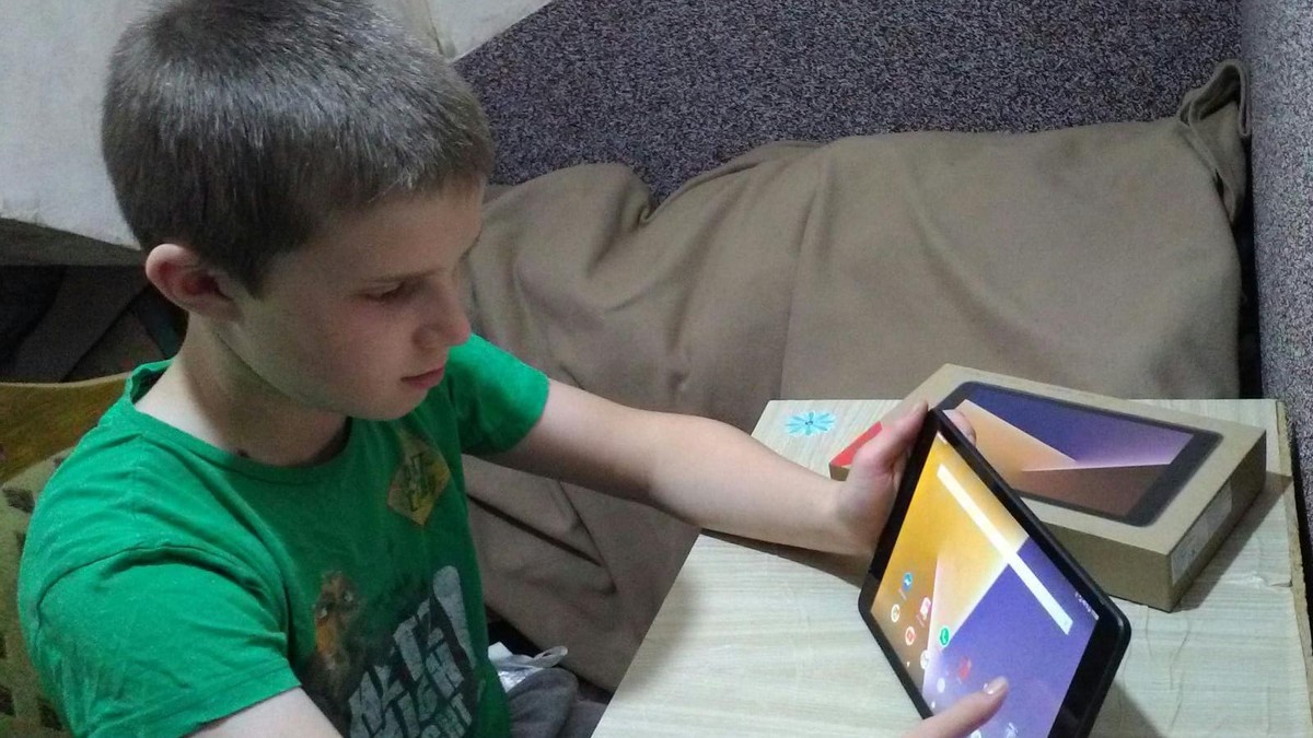 Copiii din Dorna Cândrenilor au primit tablete din banii de navetă ai profesorilor. Copil care își face lecțiile pe tabletă