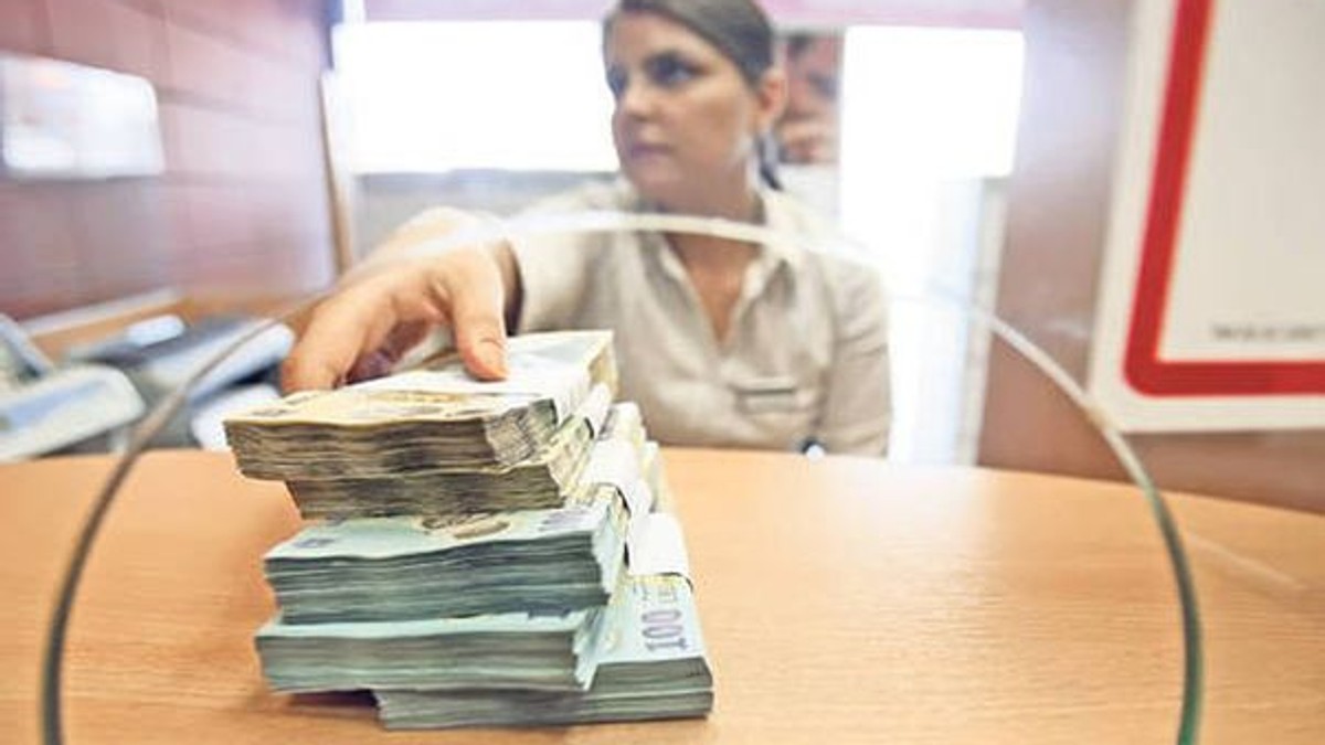 ANPC a amendat 15 bănci din România pentru publicitate înșelătoare și probleme la contracte. Care sunt acestea și ce au descoperit inspectorii ANPC. Ghișeu bancar cu mai multe teancuri de bani