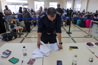 A Palestinian border guard checks the documents of dual nationals and foreigners as they wait to cross the Rafah border crossing with Egypt, in the southern Gaza Strip, on November 7, 2023, amid the ongoing battles between Irael and the militant group Hamas.,Image: 820433462, License: Rights-managed, Restrictions: , Model Release: no