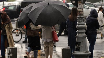 oameni la semafor cu umbrelele desfacute, in ploaie