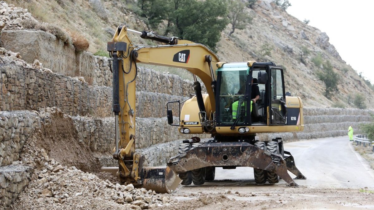 Un buldoexcavator lucrează la ridicarea unor diguri de piatră pe marginea unui drum, august 2024