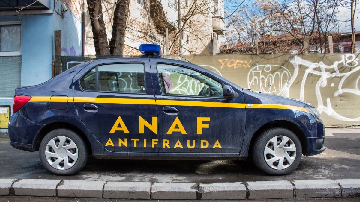 Masina albastru unchis a ANAF, Agentia Nationala Antifrauda, parcata pe o strada, in spate se vad copaci fara frunze, toamna