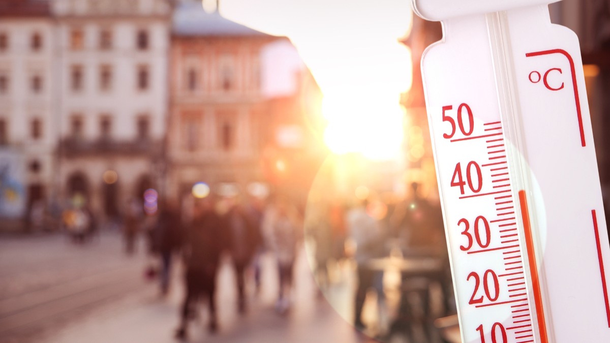 Imaginea prezintă un termometru de exterior indicând o temperatură de peste 40 de grade Celsius, pe fundalul blurat al unei străzi aglomerate dintr-un oraș însorit.