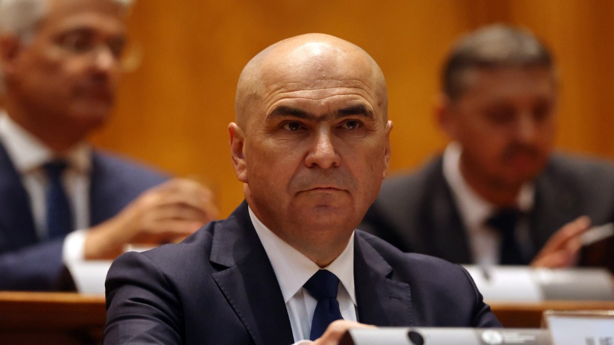 Premierul Ilie Bolojan, în costum negru, cămașă albă și cravată