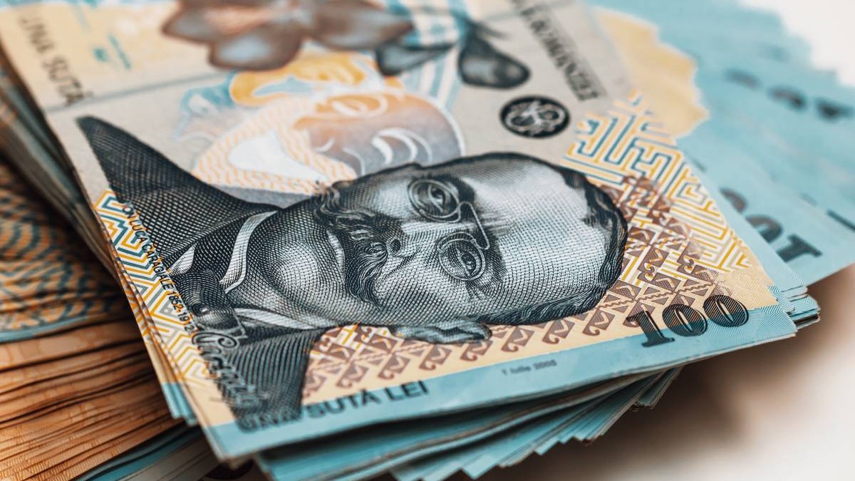 Zeci de hârtii de 100 de lei întinse pe o masă