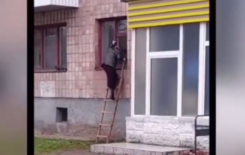 O bunicuță din Ucraina iese din bloc pe geam, cu scara, după ce la intrare a fost instalat un interfon