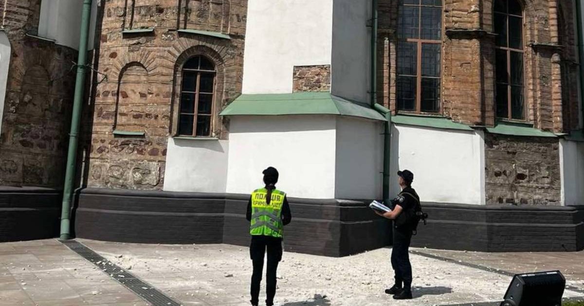 Doi angajați veniți în fața Catedralei Sfânta Sofia să analizeze pagubele după loviturile asupra Kievului, se vede pe asfalt cum bucăți din fațada clădirii au căzut.