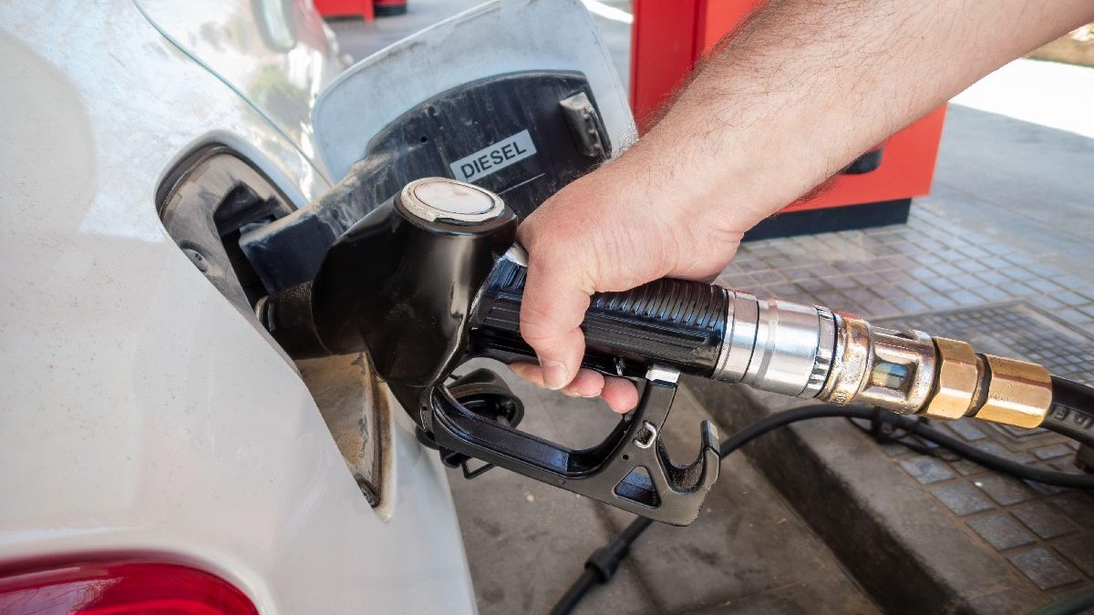 O persoană alimentează carburant cu pistolul introdus în fanta de la rezervorul unei mașini albe, într-o benzinărie