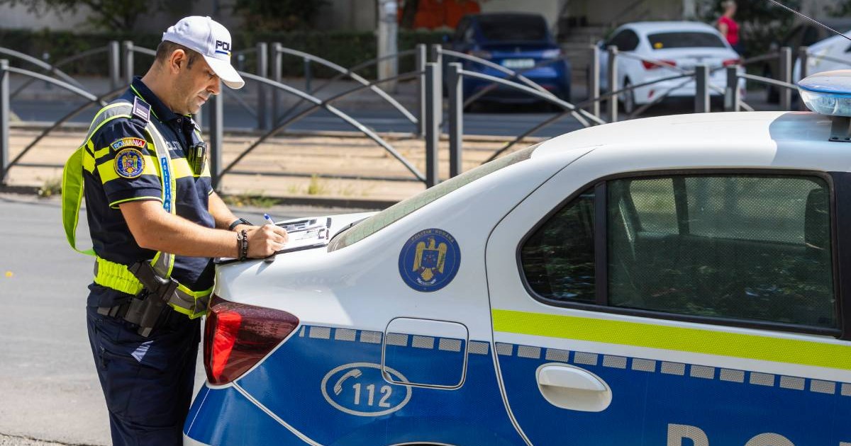 Agent al Poliției Rutiere, aflat în spatele unei autospeciale, scriind un proces verbal pe pareta portbagajului mașinii. Bărbatul este îmbrăcat în uniforma corespunzătoare polițiștilor români, cu o șapcă albă pe cap.