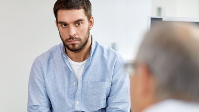 young male patient talking to doctor at hospital