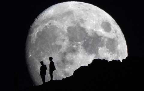 Luna în creștere răsare în spatele unor oameni aflați aproape de vârful lui Arthur's Seat din Parcul Holyrood, Edinburgh. Sursă foto: Hepta.