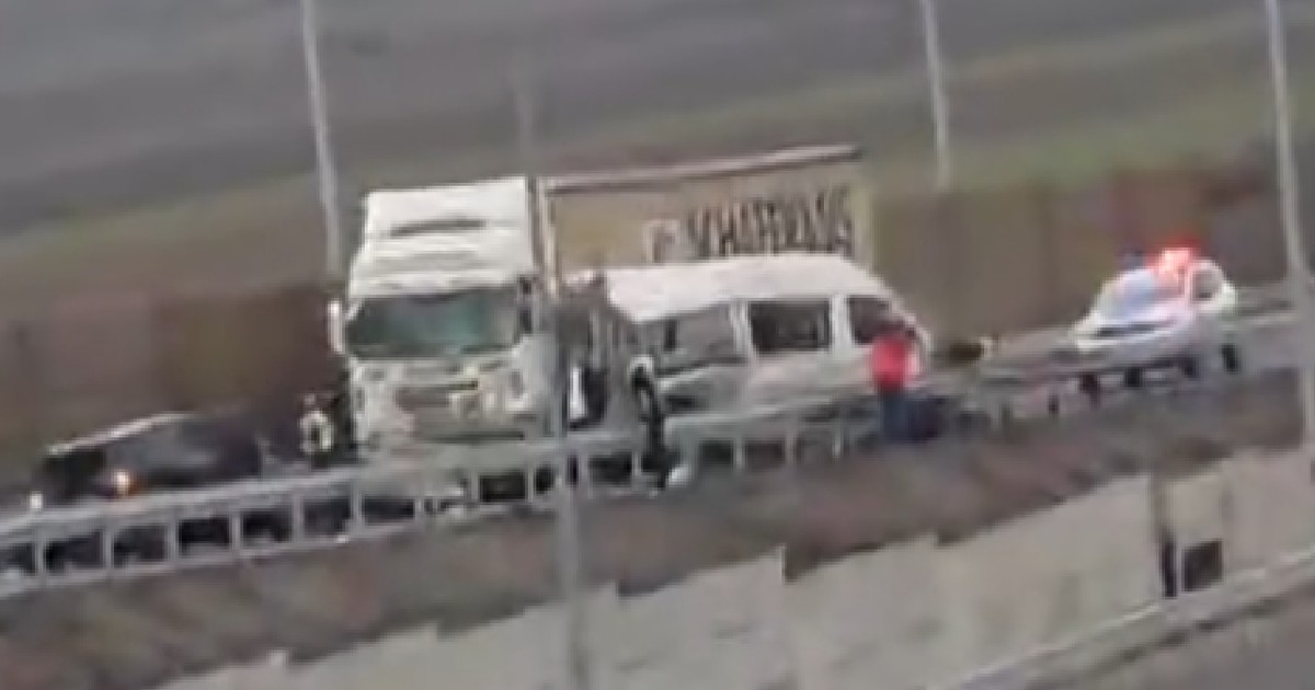 Imaginea surprinde un accident rutier pe autostradă, în care sunt implicate un camion de mare tonaj și o dubiță, oprite pe banda de circulație, în apropierea parapetului median. În zonă se află și un echipaj de poliție cu semnalele luminoase pornite, iar câteva persoane se pot vedea în afara vehiculelor.