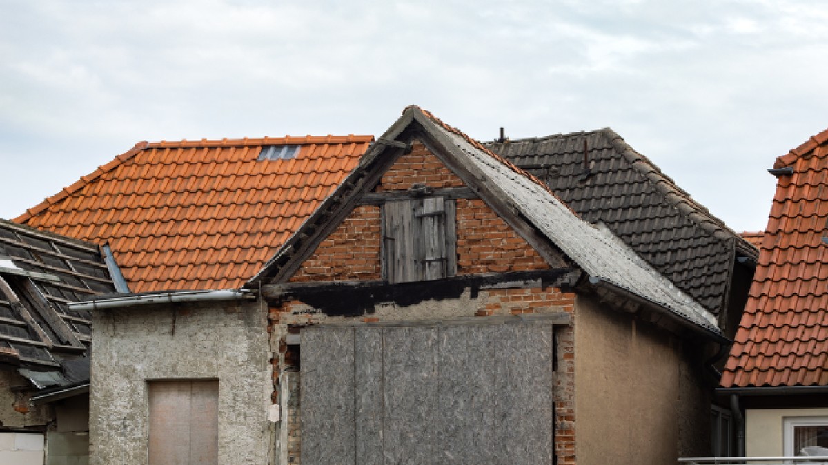 Clădire veche în ruină, cu uși și ferestre astupate cu scânduri. Exteriorul este deteriorat și în stare foarte proastă.