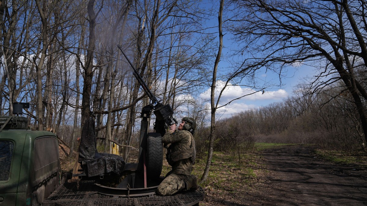 Poză cu un soldat rus, ținând în mâini o armă, lângă un vehicul de luptă
