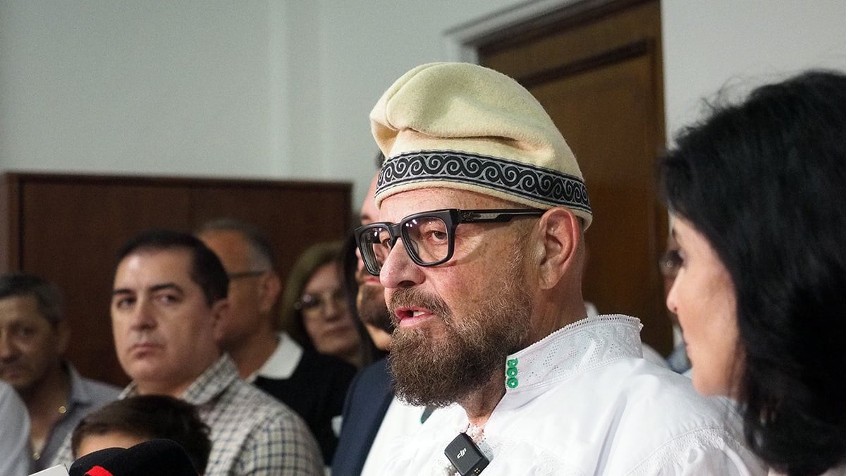 Un barbat imbt=racat in camasa alba si o caciula traditionala pe cap
