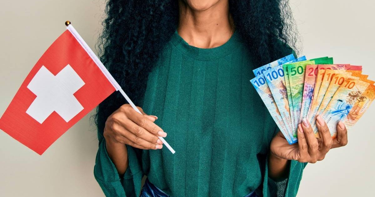 Femeie afro-americană, în bluza verde, ținând steagul Elveției intr-o mana și bancnote în franci in cealalta