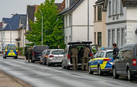 Mașini de poliție parcate în fața unei case din Germania, în timpul unei interventii