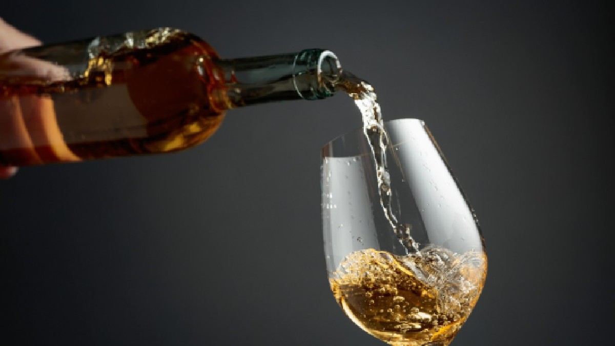 Vin alb este turnat dintr-o sticlă într-un pahar