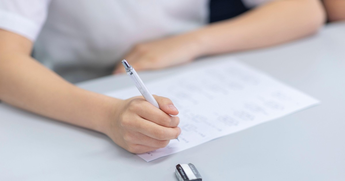 Imagine cu un elev în bancă în timpul unui examen. Ține un pix în mână