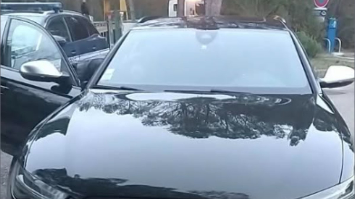 Un Audi negru parcat. Lângă acesta se află o mașină de jandarmerie.