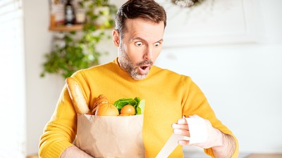 Surprised,Man,Looking,At,Store,Receipt,After,Shopping,,Holding,A