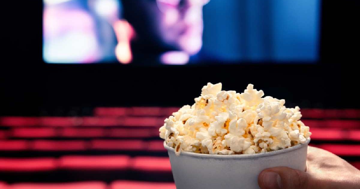 O persoană ține popcorn în mână la cinema