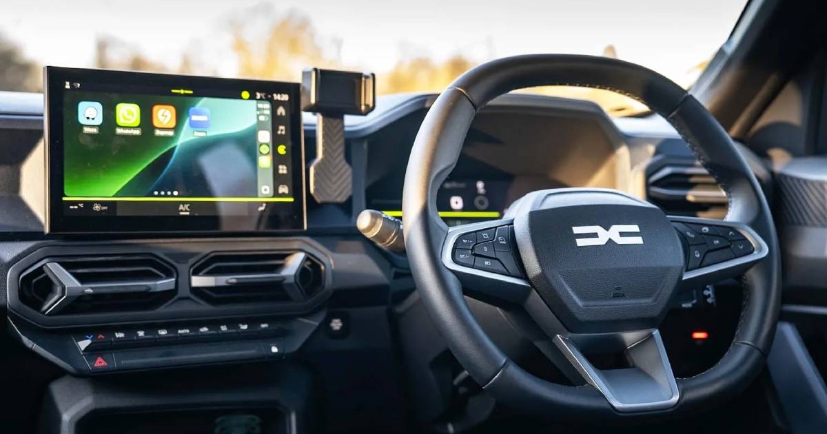 interior masina electrica dacia duster, pe volan se observa noul logo dacia, se observa consola centrala touchscreen