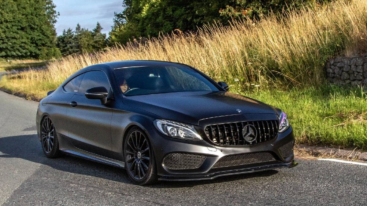 Un Mercedes-AMG C63 rulează pe o șosea mărginită de o câmpie