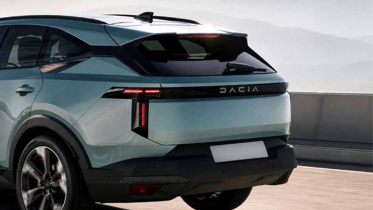 Imagine cu partea din spate a unei mașini Dacia de culoare verde-albăstruie, surprinsă din lateral-spate, pe un drum. Se văd stopurile LED roșii, inscripția „DACIA” pe hayon, geamul fumuriu și bara de protecție neagră. Plăcuța de înmatriculare este albă și fără text.