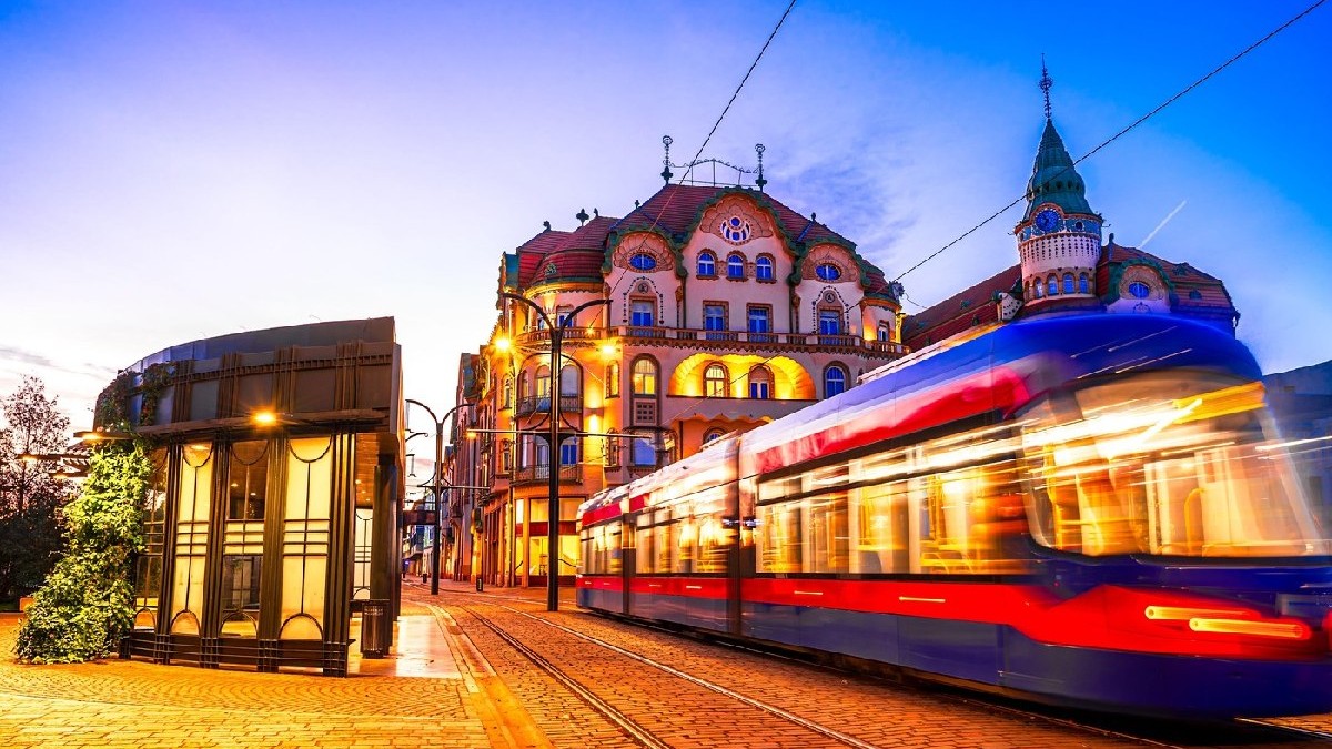 Oradea, România: Dimineața tramvai în mișcare blur în Piața Unirii, cu arhitectura orașului frumos de Crisana, Transilvania, răsărit de soare cer colorat, Europa