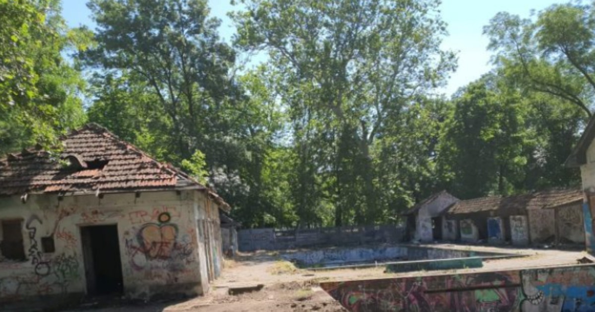 Ruinele abandonate ale bazei „Uszoda” din Timișoara. Sunt evidențiate clădiri deteriorate și bazine goale acoperite de graffiti colorat.